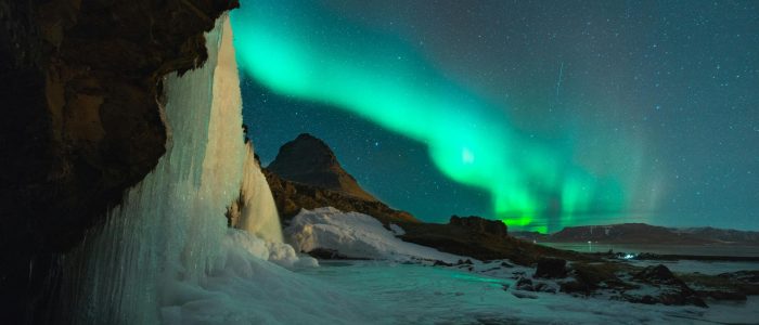 Stunning view of the Northern Lights over Kirkjufell mountain and frozen waterfall in Iceland. Perfect for nature lovers.